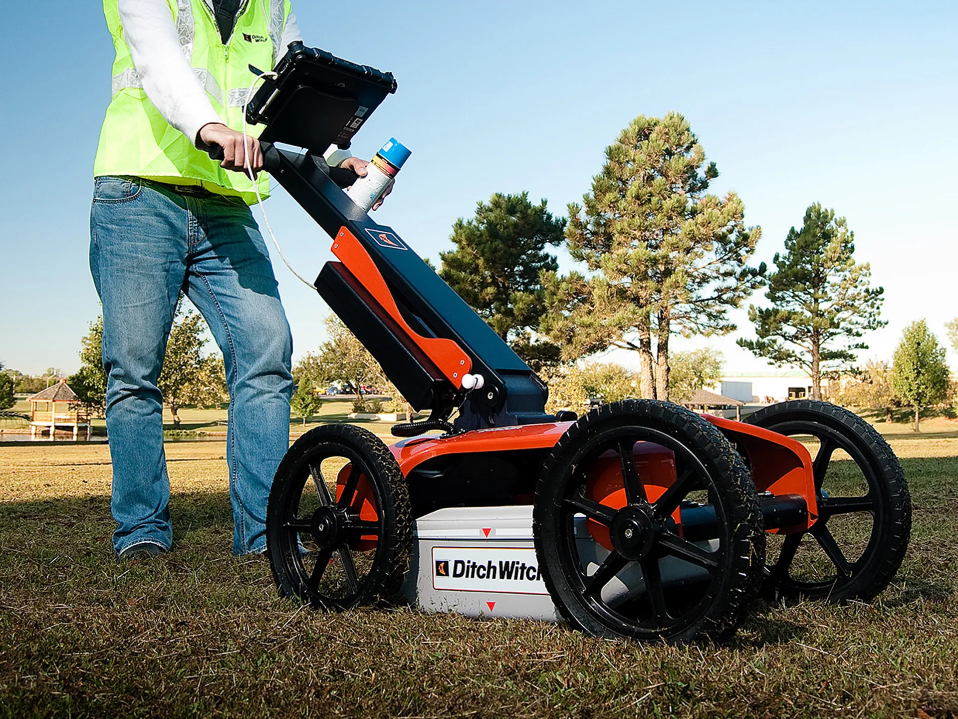 A person pushing a wheeled ground-penetrating radar cart across a ploughed field