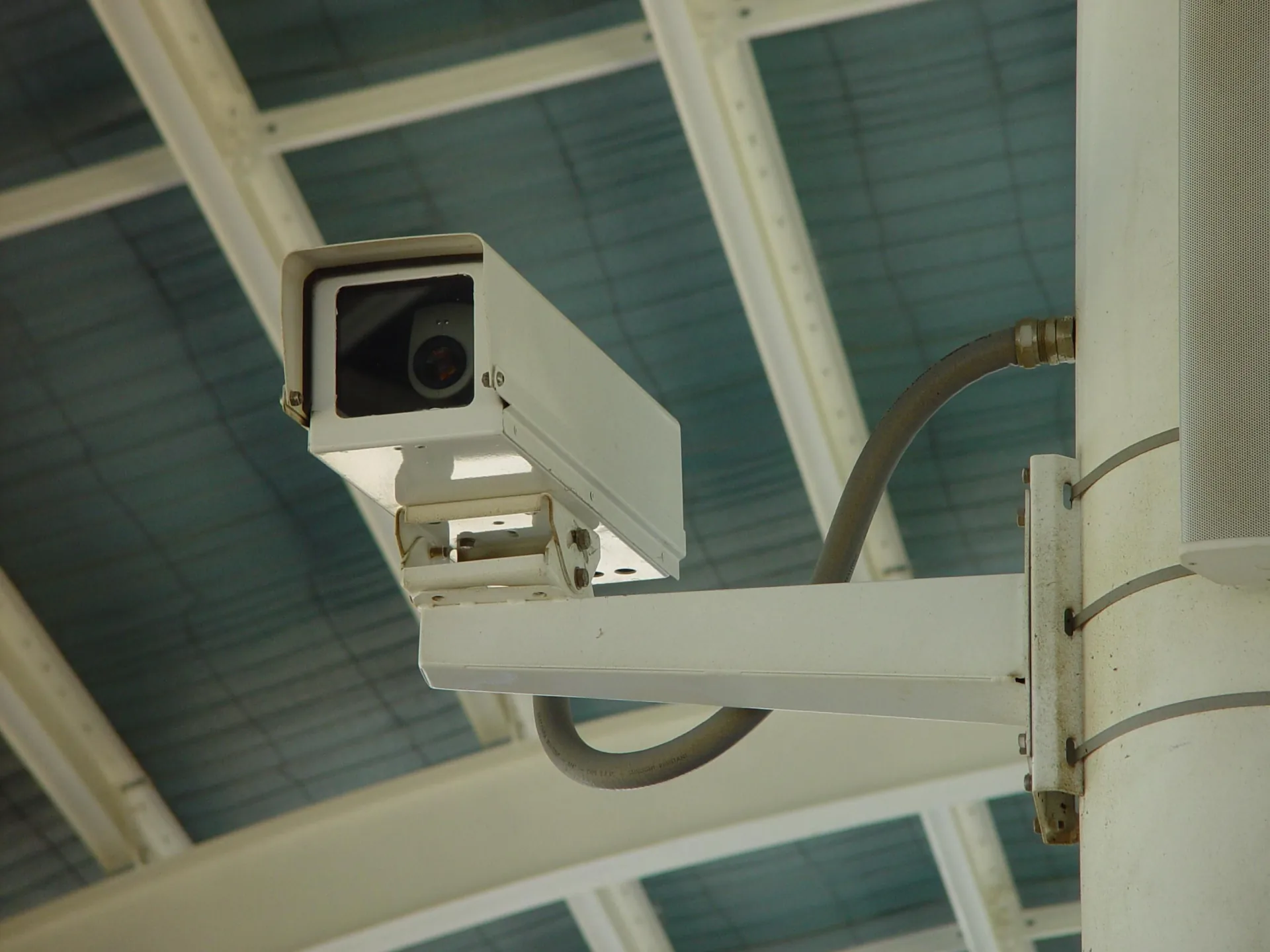 A wall-mounted surveillance camera pointed toward a public area
