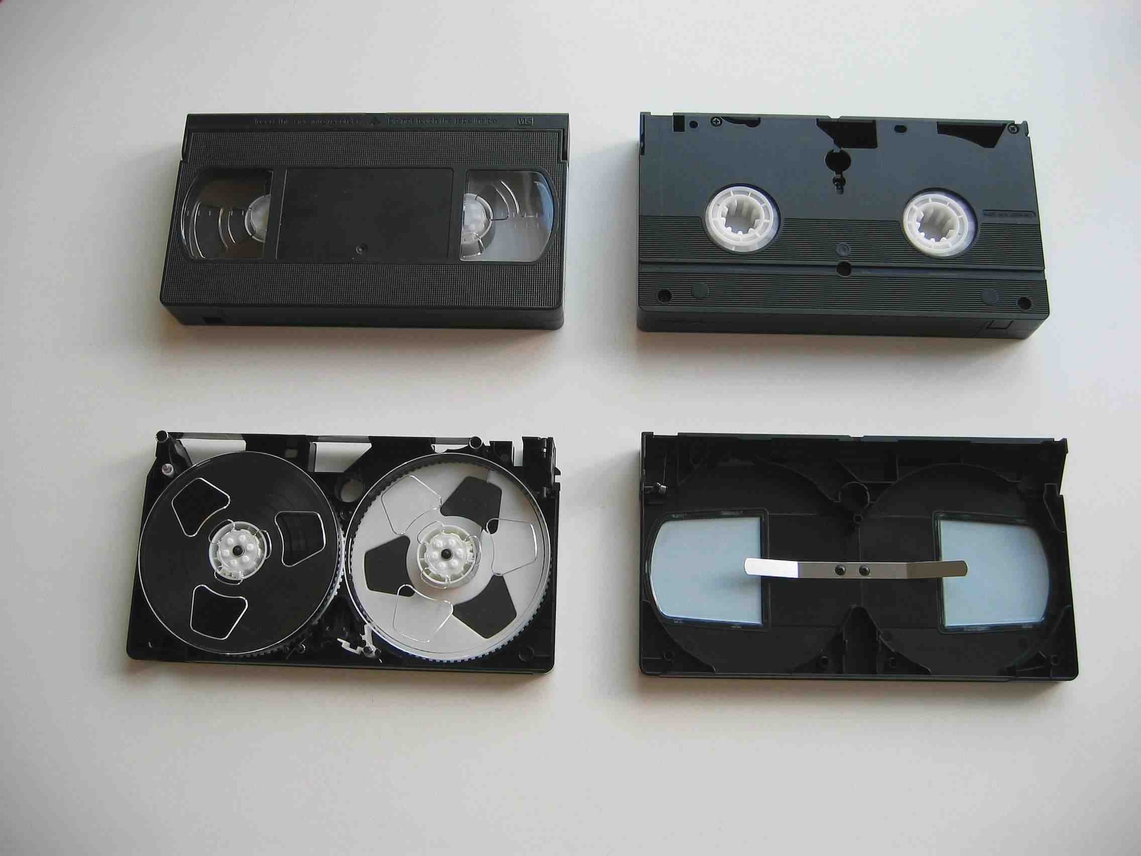 Two VHS cassettes, one opened to show the magnetic tape and reel mechanism