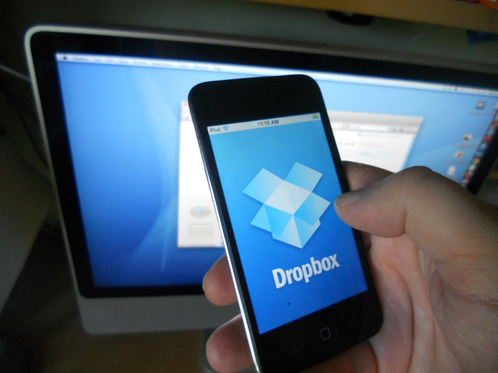 Dropbox app displayed on an iPhone in front of a laptop